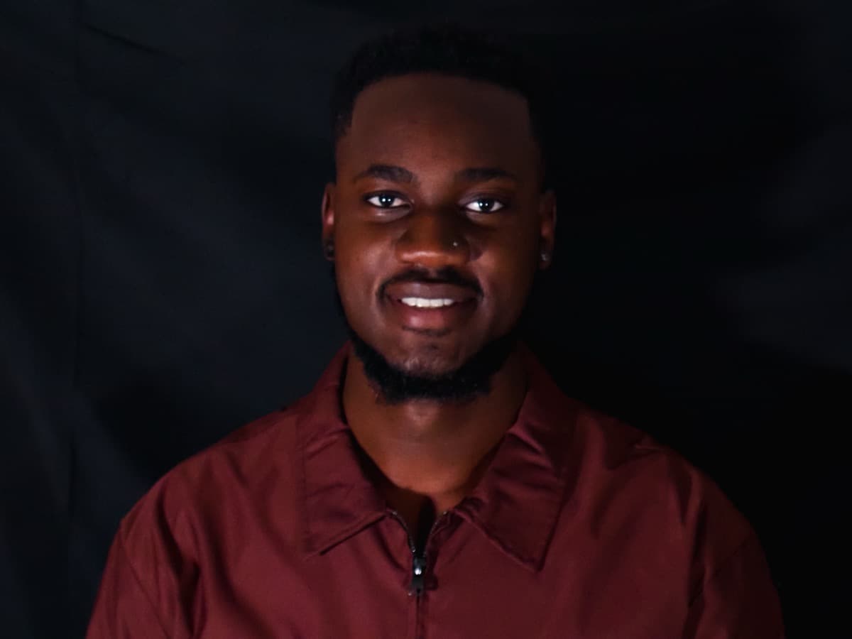 Nickoy Anthony in a maroon jacket against a black studio backdrop